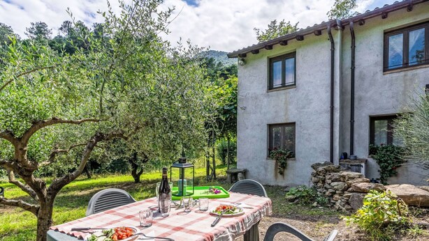 An outdoor dining area with a table set for two, surrounded by greenery and a stone wall. - Wonderful private villa for 6 guests with WIFI, TV, patio and pets allowed (Rialto)