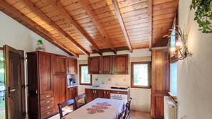A wooden kitchen with a dining table, cabinets, and a window.