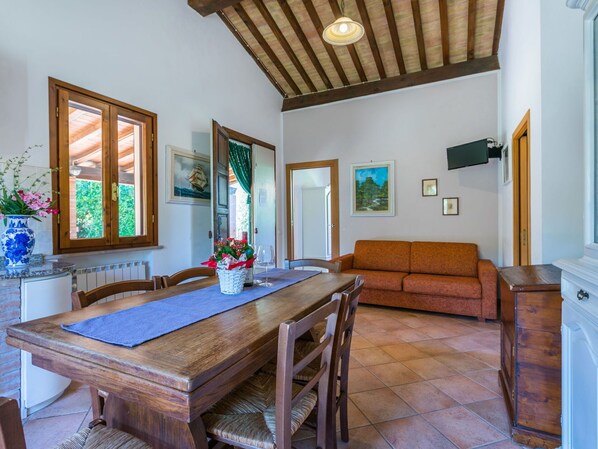Een eethoek met een houten tafel, stoelen en een buffet. Achterin staat een bank en een kast.