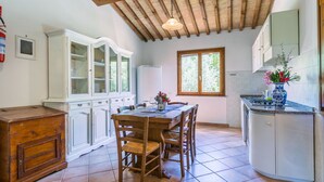 A kitchen with a wooden table, chairs, a white cabinet, and a window. - Wonderful private villa for 6 people with pool, terrace and pets allowed (Casale Marittimo)