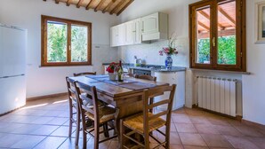 A kitchen with a wooden table, chairs, and a window with a view of greenery. - Wonderful private villa for 6 people with pool, terrace and pets allowed (Casale Marittimo)