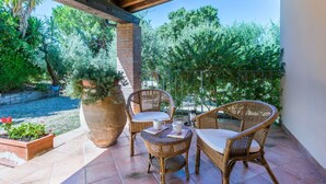 A covered patio with wicker furniture, a large planter, and a view of a garden and trees. - Wonderful private villa for 6 people with pool, terrace and pets allowed (Casale Marittimo)