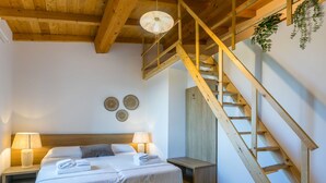 Ein Schlafzimmer mit einem hölzernen Bett, zwei Nachttischen mit Lampen, einer Holztreppe und einer Wandpflanze.