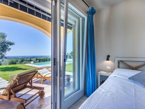 A bedroom with a large sliding glass door leading to a balcony with a view of a pool and greenery. - Wonderful private villa for 6 people with A/C, WIFI, private pool, TV, patio and panoramic view (Castagneto Carducci)