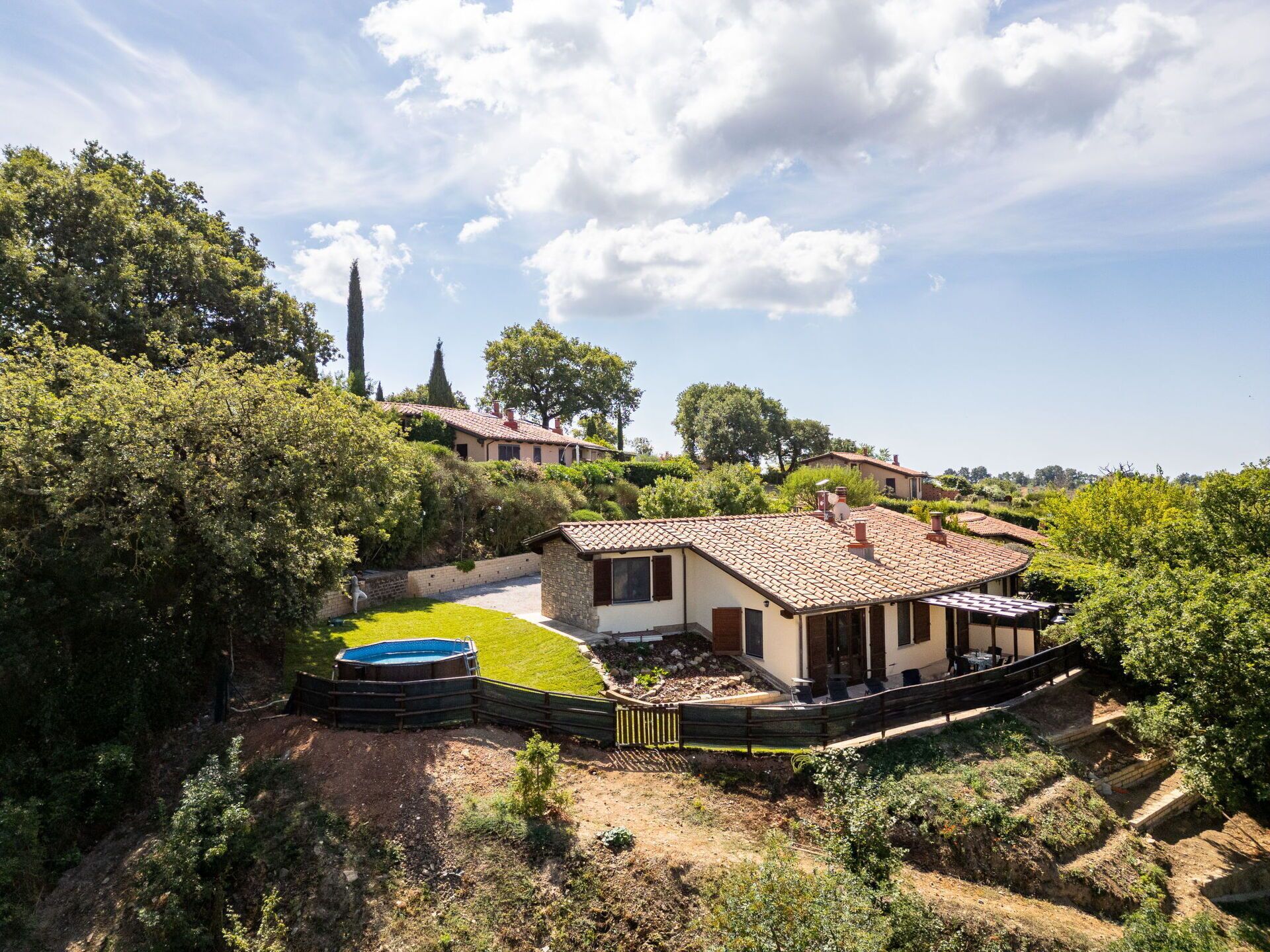 Una villa con piscina, rodeada de exuberante vegetación y colinas.