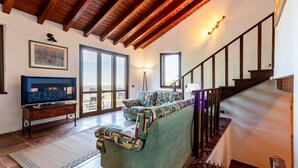 A living room with a sofa, television, and a staircase. - Beautiful private villa with private pool, WIFI, A/C, hot tub, TV, patio and panoramic view (Scansano)