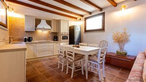 A kitchen with wooden beams, white cabinets, a dining table with chairs, and a sofa. - Beautiful private villa with private pool, WIFI, A/C, hot tub, TV, patio and panoramic view (Scansano)