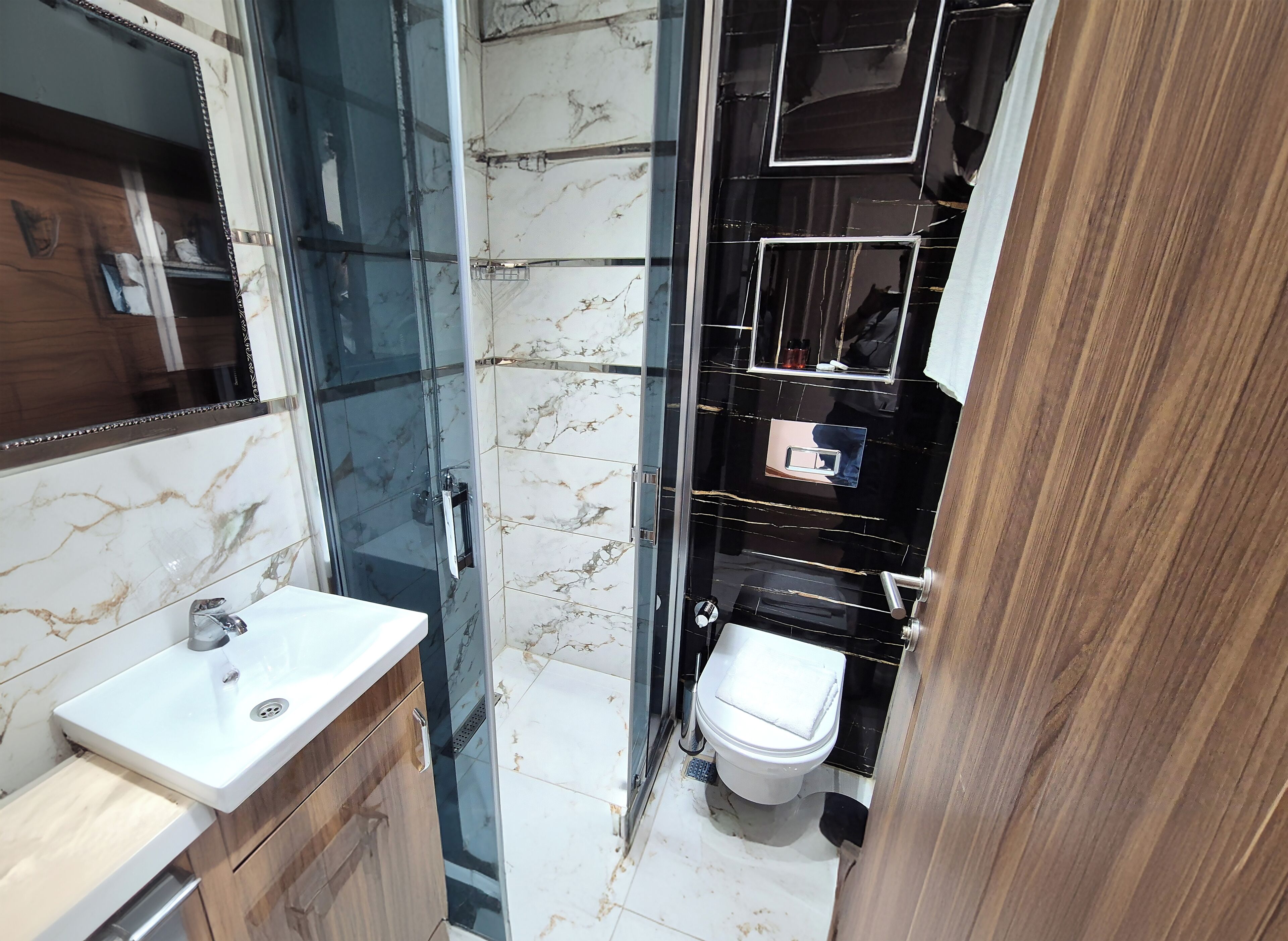 A bathroom with a glass shower enclosure, a white sink, and a toilet.