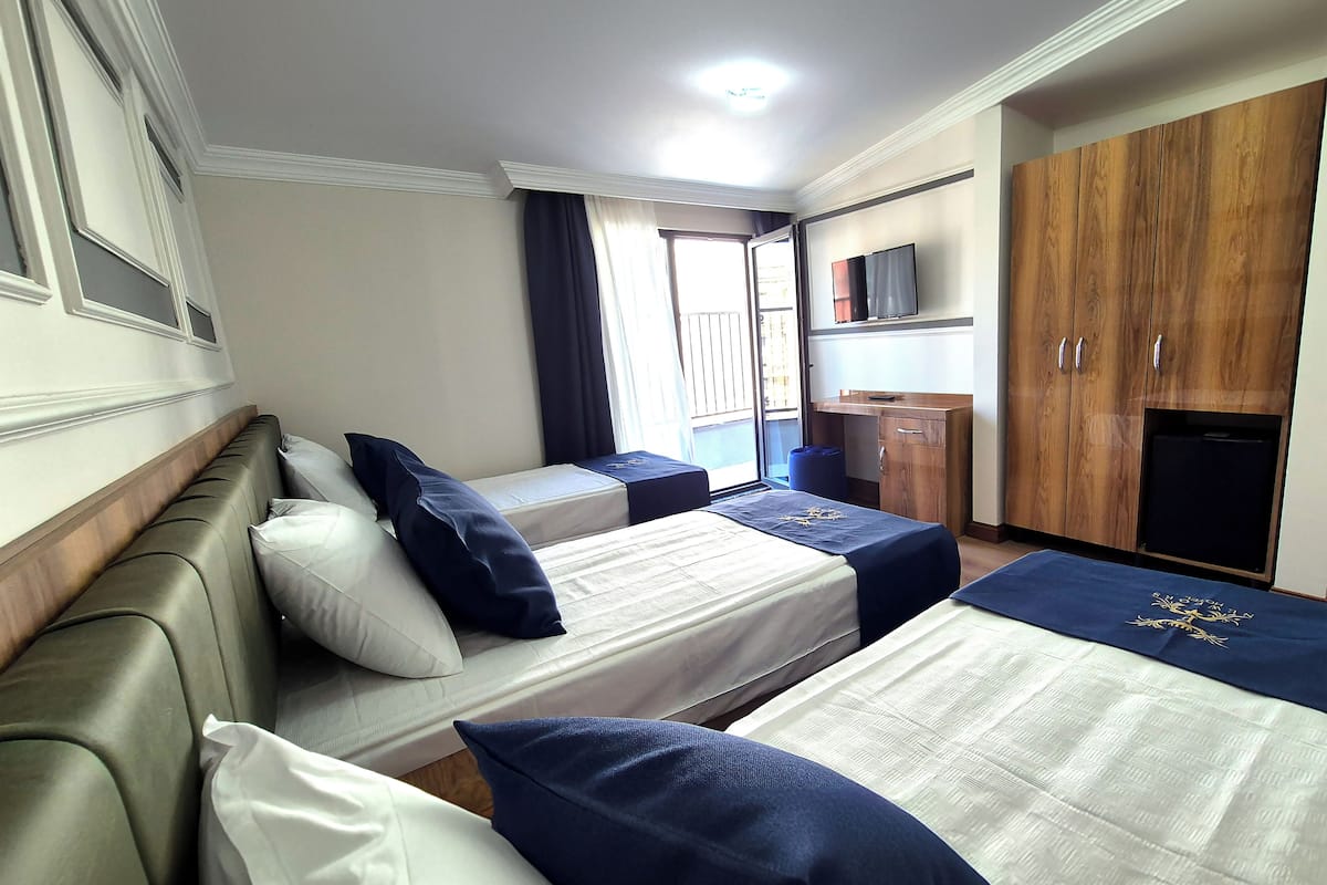 A hotel room with two beds, a sofa, a desk, and a wardrobe.