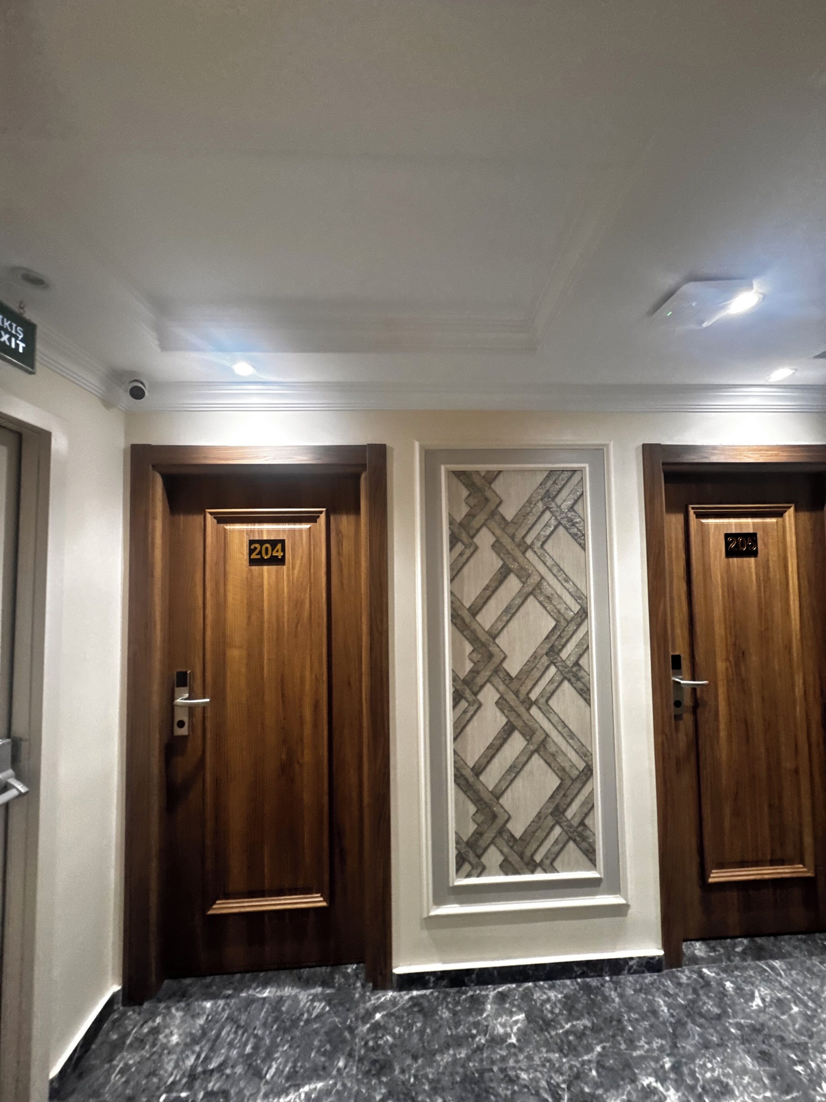 Un couloir d’hôtel avec trois portes en bois, chacune portant un numéro.