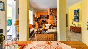 Ein Wohnzimmer mit Sofa, Sesseln, einem Couchtisch und einer Treppe, die in eine andere Ebene führt.
