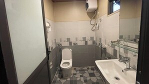 Pieni kylpyhuone, jossa on wc, pesuallas ja käsienkuivaaja.