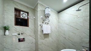 Baño con inodoro, lavabo y ducha. Hay un toallero con toallas y una ventana pequeña sobre el inodoro.