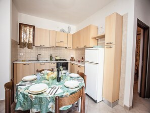 Een koelkast, een oven, een kookplaat, kookgerei, borden en bestek