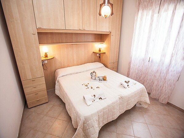A bedroom with a bed, bedside tables, a wardrobe, and a window with curtains.