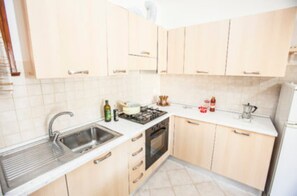 Een koelkast, een oven, een kookplaat, kookgerei, borden en bestek