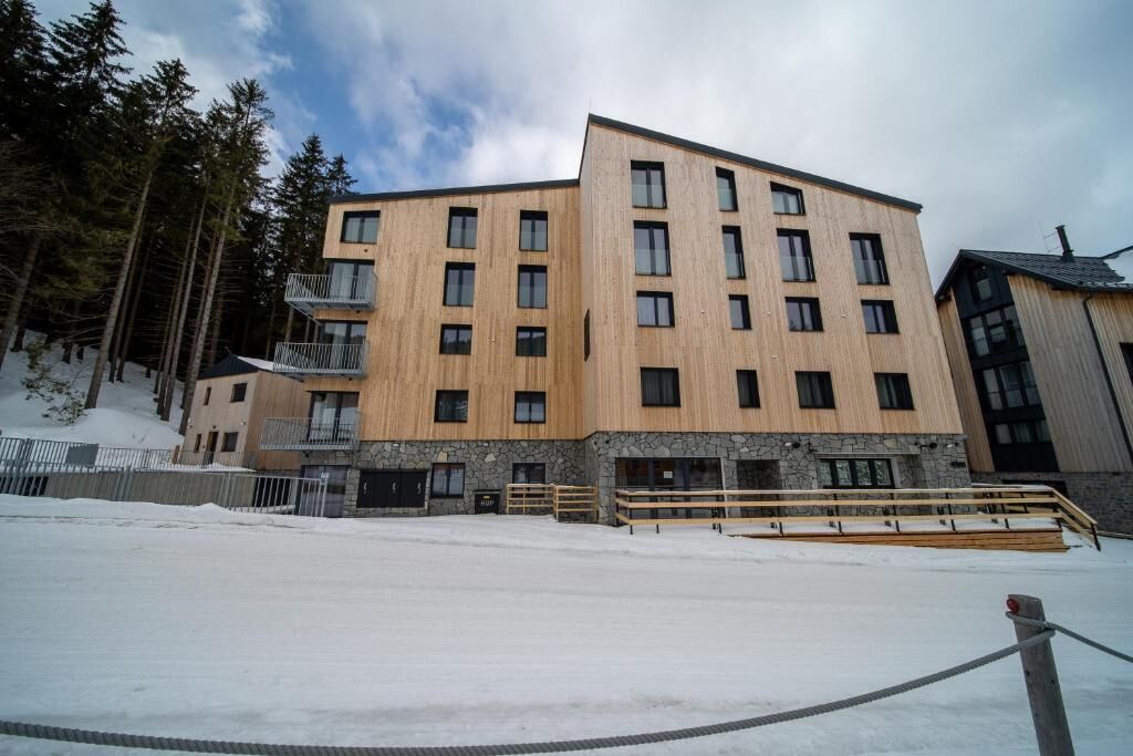 A multi-story building with a wooden facade, stone base, and balconies.