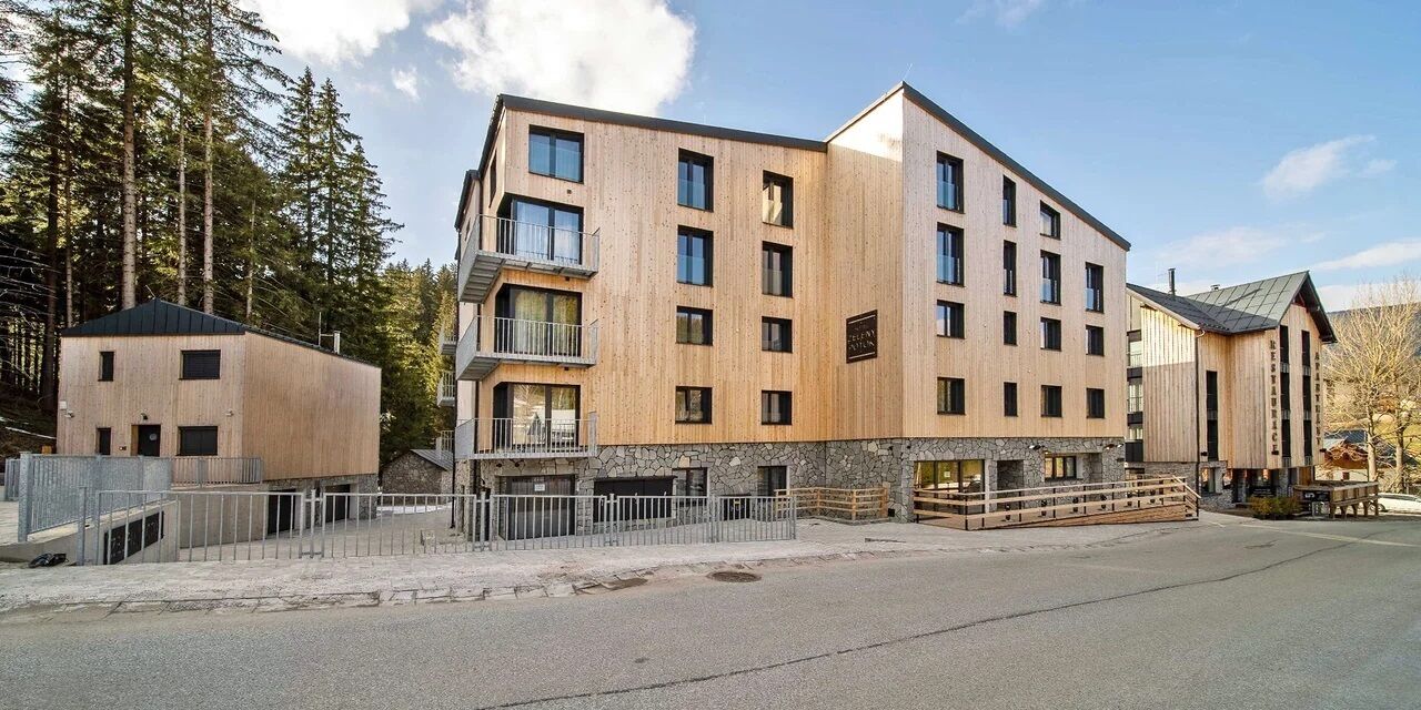 Et hotel med flere etager, en træfacade, balkoner og en stensokkel.