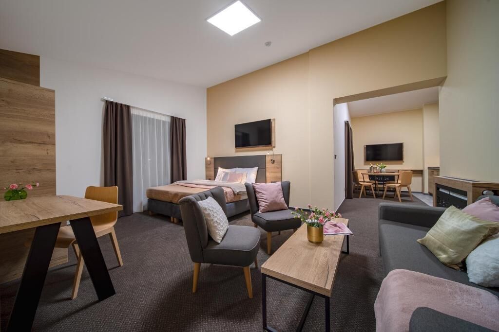 A modern hotel room with a bed, a desk, a sofa, and a dining table.