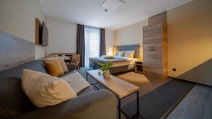 A modern hotel room with a sofa, a bed, a desk, and a wardrobe. - Hotel Zelený Potok (Pec pod Snezkou)