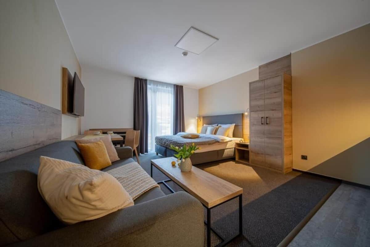 Una habitación de hotel moderna con sofá, cama, escritorio y armario.