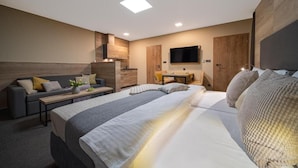 A modern hotel room with a large bed, a sofa, a desk, and a TV. - Hotel Zelený Potok (Pec pod Snezkou)