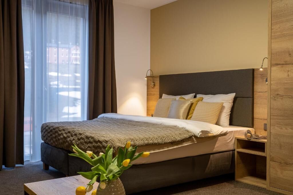 Ein modernes Schlafzimmer mit einem großen Bett, einem Nachttisch und einem Fenster mit Vorhängen.