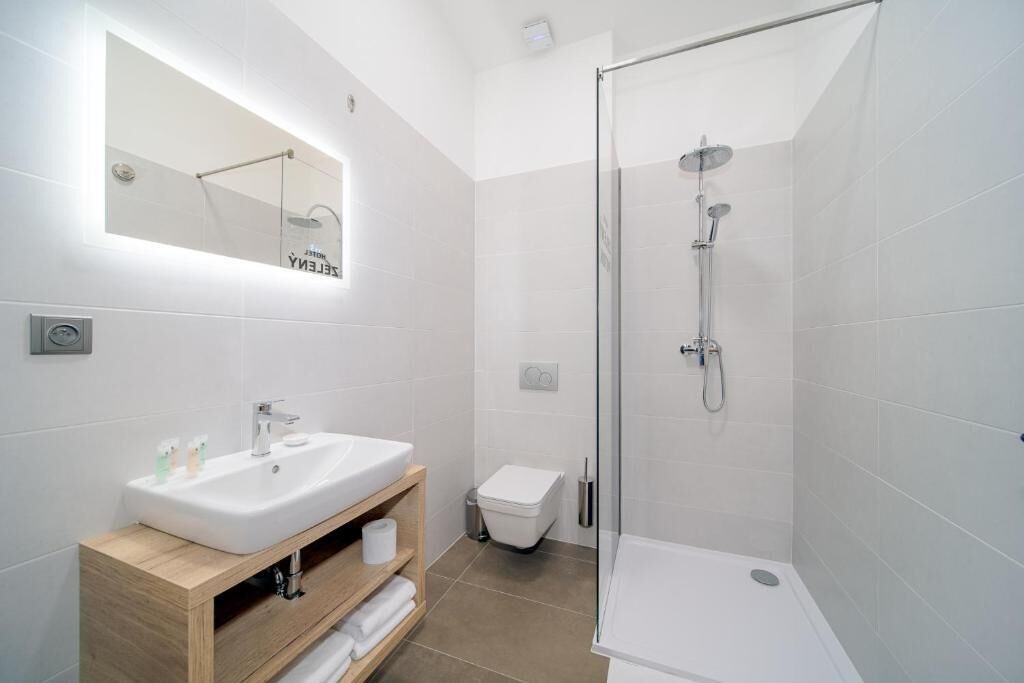 Et moderne badeværelse med bruseniche i glas, en hvid vask og et spejl over vasken.