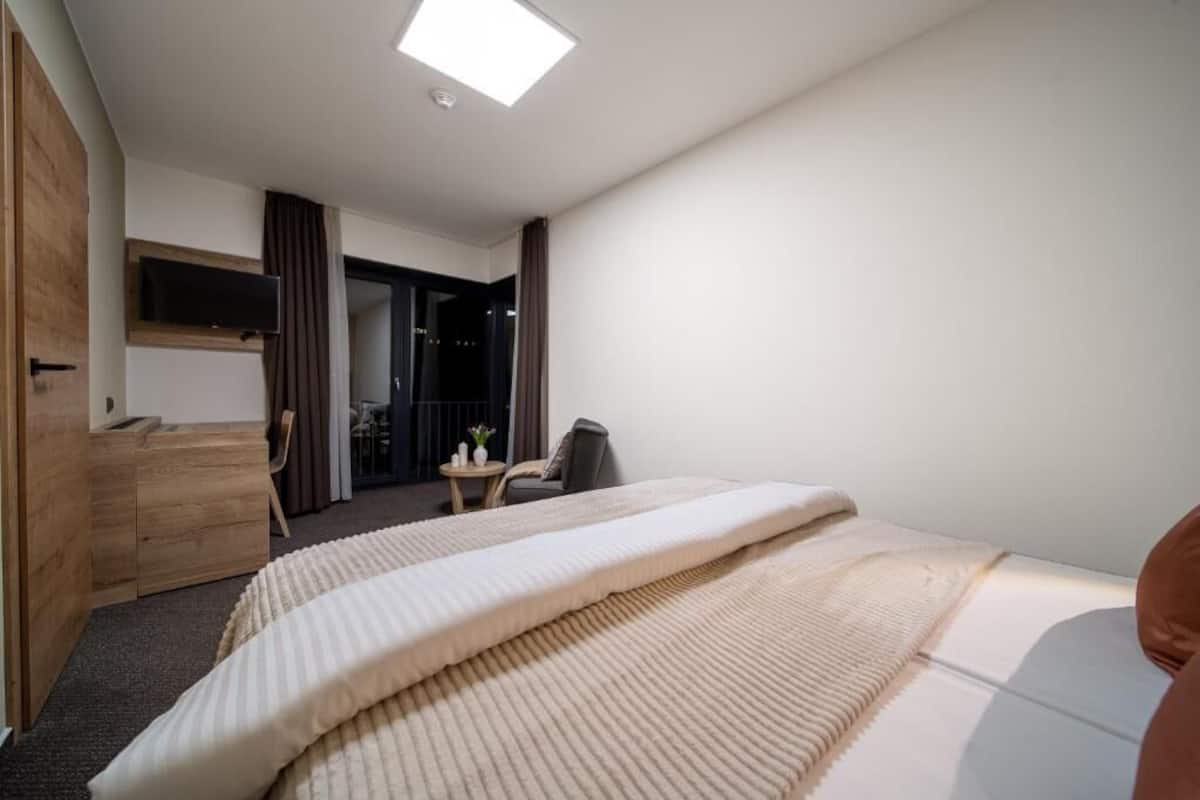 Una habitación de hotel moderna con una cama grande, un escritorio y un televisor.