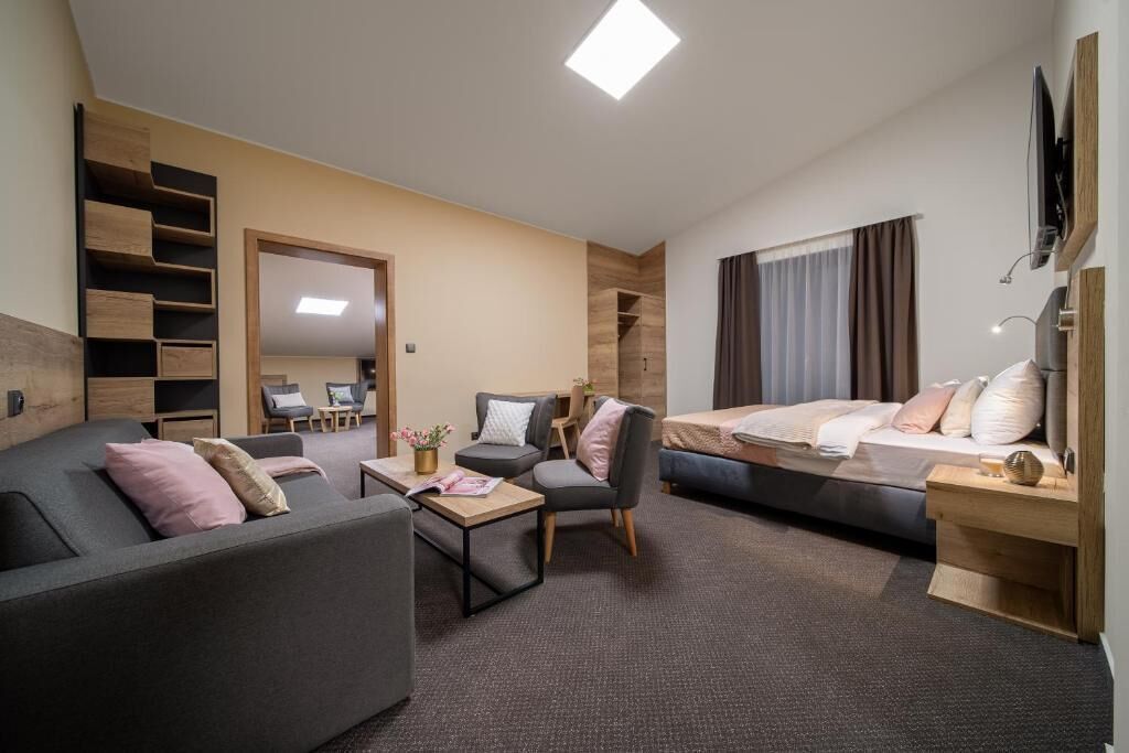 Ett modernt hotellrum med en soffa, en säng, ett skrivbord och en tv.