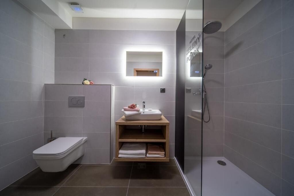 Un baño moderno con inodoro, lavamanos con espejo y zona de ducha.