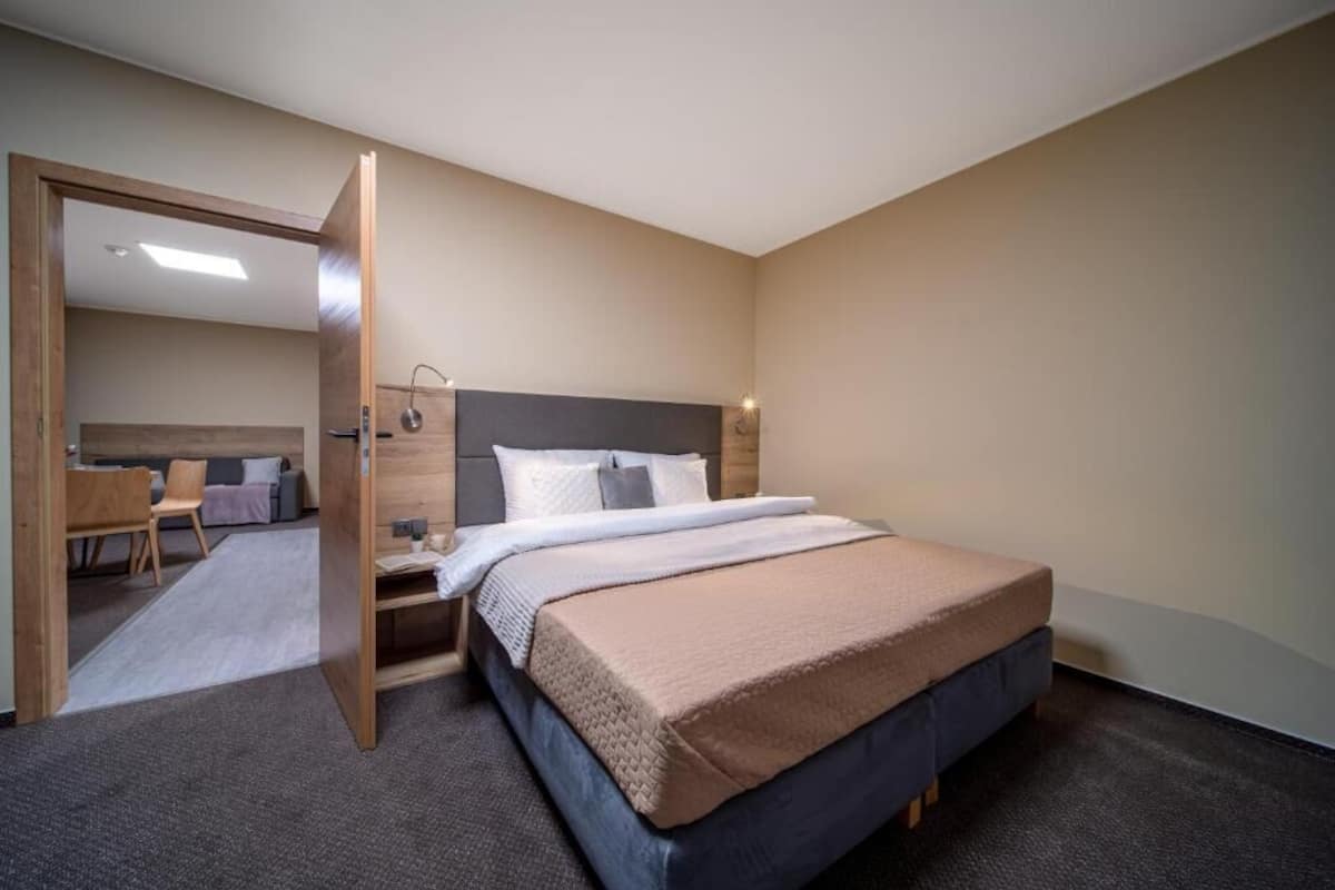 Una habitación de hotel moderna con una cama grande, un cabecero de madera, un escritorio y una silla.
