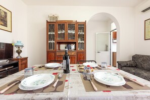 A dining area with a table set for four, a cabinet with glass doors, and a sofa in the background. - 4089 Villino Mondonuovo by Barbarhouse (Nardò)