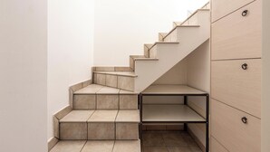 A modern staircase with a minimalist design, leading to a landing with a metal shelf and wooden cabinets. - 4089 Villino Mondonuovo by Barbarhouse (Nardò)
