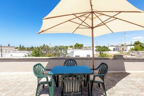 A rooftop terrace with a table and chairs under a large umbrella, overlooking a residential area. - 4089 Villino Mondonuovo by Barbarhouse (Nardò)