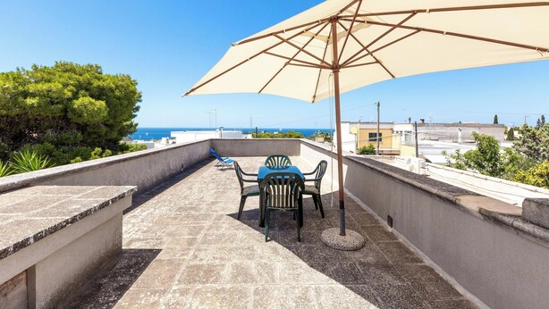 A terrace with a table and chairs under a large umbrella, overlooking a coastal view. - 4089 Villino Mondonuovo by Barbarhouse (Nardò)