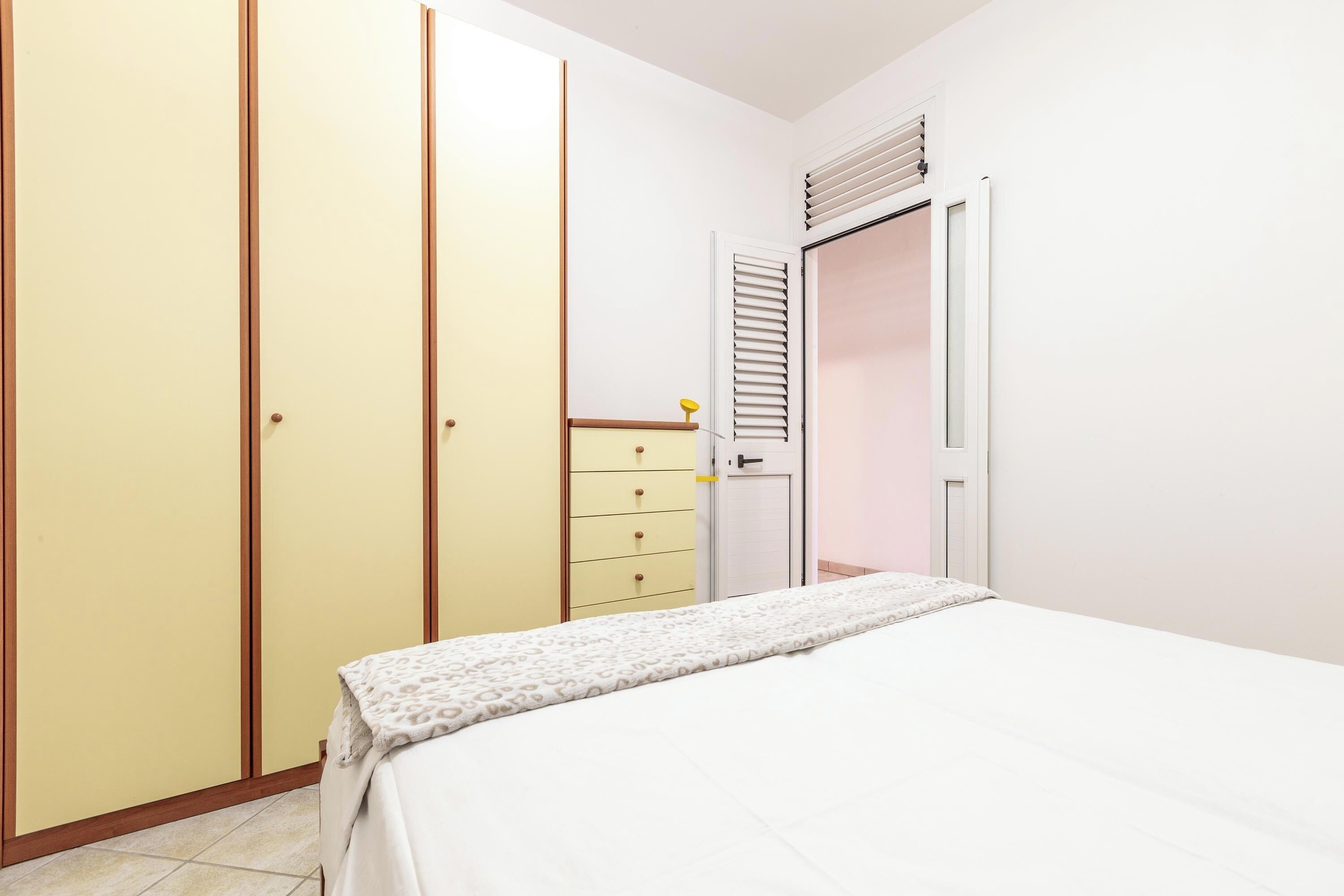 A bedroom with a bed, a wardrobe, and a dresser.