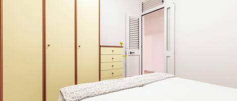 A bedroom with a bed, a wardrobe, and a dresser.