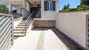 A modern building with a staircase leading to a covered entrance, a small outdoor seating area, and a view of the surrounding greenery. - 4089 Villino Mondonuovo by Barbarhouse (Nard ò)