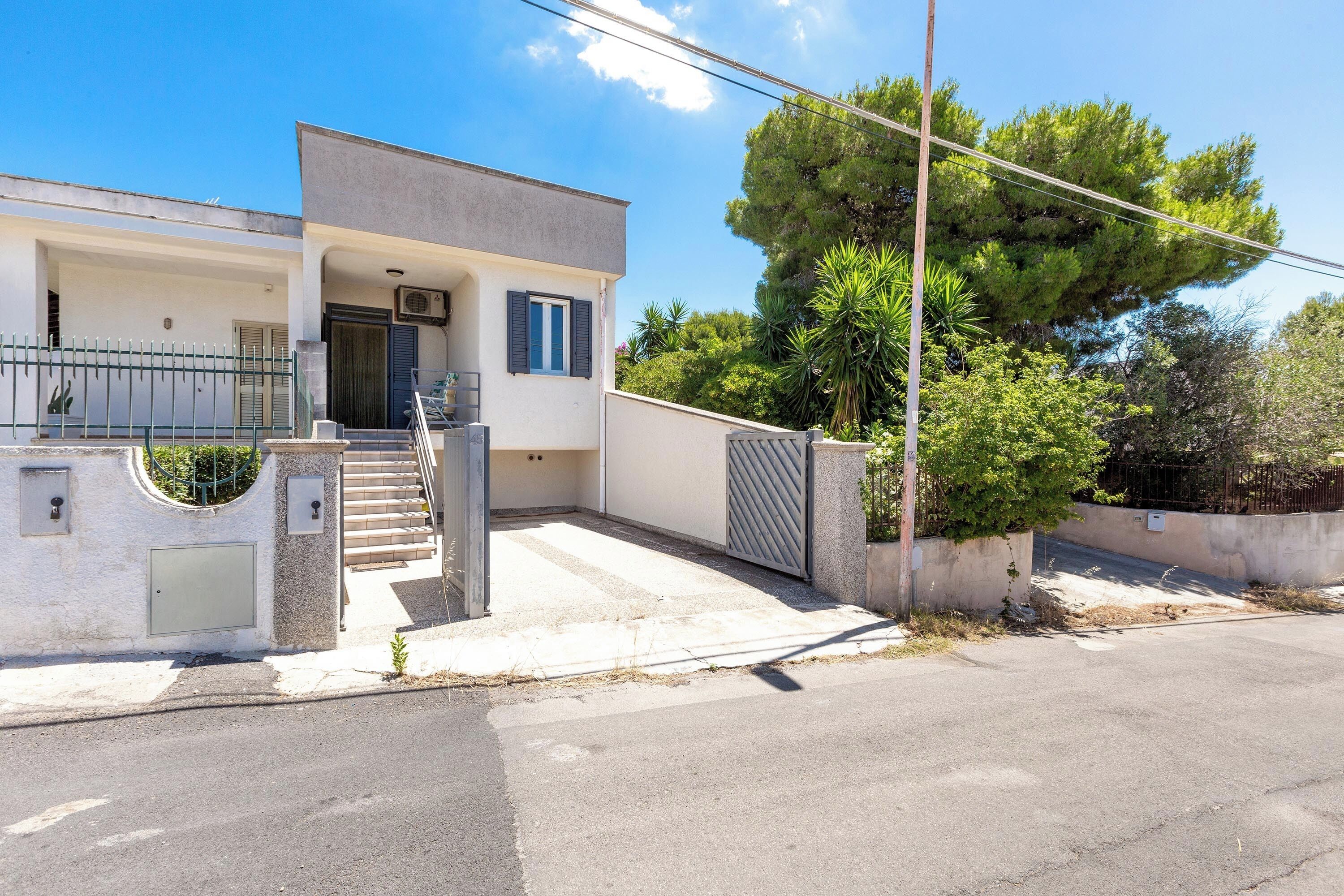 Une maison moderne à deux étages, dotée d’une entrée principale, d’un escalier et d’une allée menant à une porte.