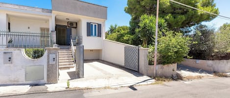 A modern two-story house with a front entrance, a staircase, and a gated driveway.