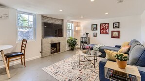 A living room with a fireplace, a sofa, a coffee table, and a bookshelf. - Pet Friendly I Remodeled I Near RiNo | Sleeps 7 (Denver)