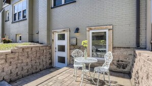 A courtyard with a white door, a window with shutters, and a small table with chairs. - Pet Friendly I Remodeled I Near RiNo | Sleeps 7 (Denver)