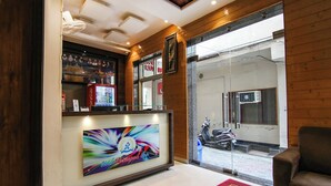 Un espace d’accueil d’hôtel avec un réfrigérateur Coca-Cola, un grand tableau encadré et un paillasson rouge.