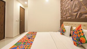 Une chambre d’hôtel avec un lit, des oreillers aux couleurs vives, un mur orné d’un motif géométrique et une porte.