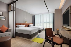 A hotel room with a bed, a desk, a chair, and a television.