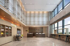 Un moderno vestíbulo de hotel con mostrador de recepción, zona de estar y grandes ventanales.