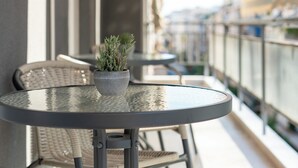 A balcony with a round table, chairs, and a potted plant.