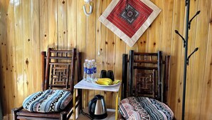 A wooden room with two wooden chairs, a small table with a kettle, a water bottle, and a banana. - Dinh Sapa Trekking & Homestay (Ta Van)