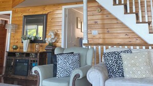 A spacious living room with a high ceiling, wooden walls, a staircase, and a fireplace. - Huron Lakefront Cottage Charming 8 bedrms 4bths 18+guests 8car/Hotub/pets . (Goderich)